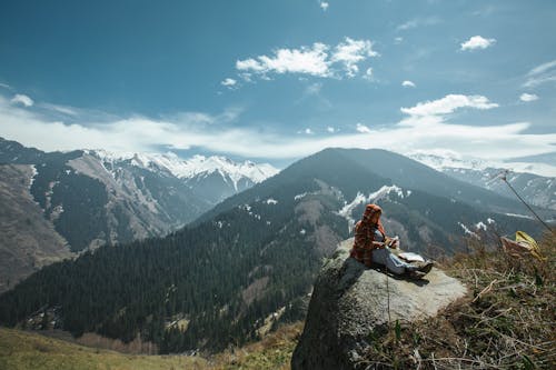Free Person Sitting on Rock Near Cliff Stock Photo