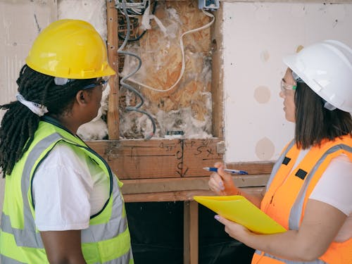 Female Engineers Looking on a Demolished Wall 