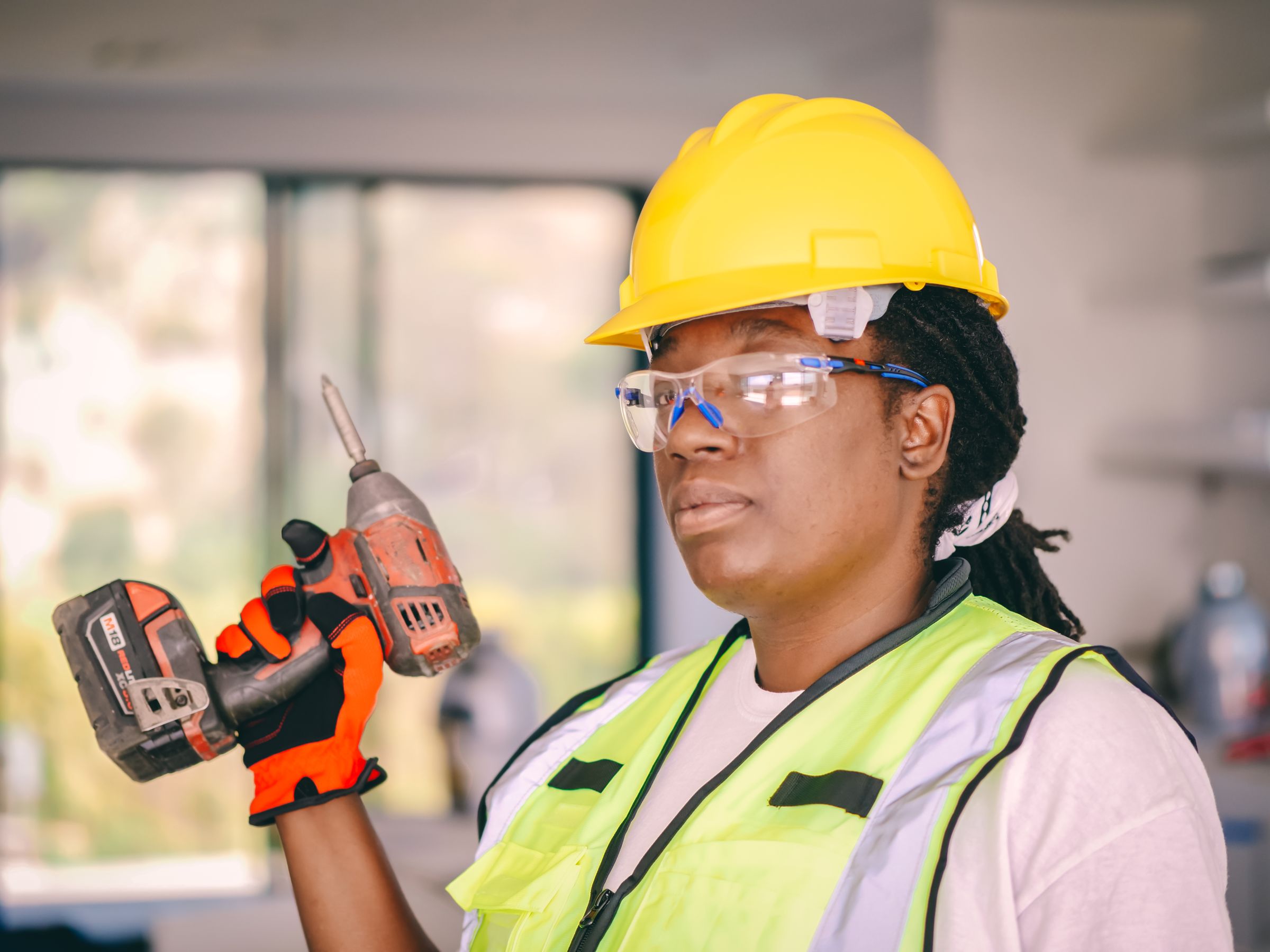 Construction worker wearing safety gear and holding a drill