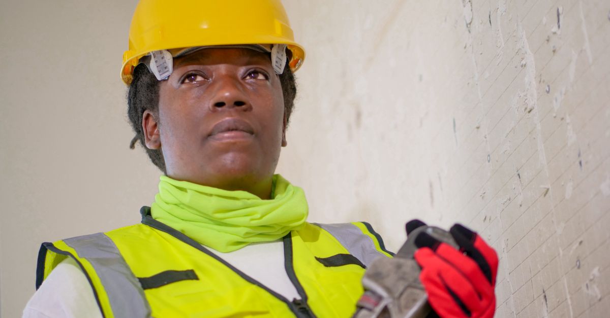 Técnica de manutenção com equipamento de segurança segurando uma chave inglesa dentro de uma instalação