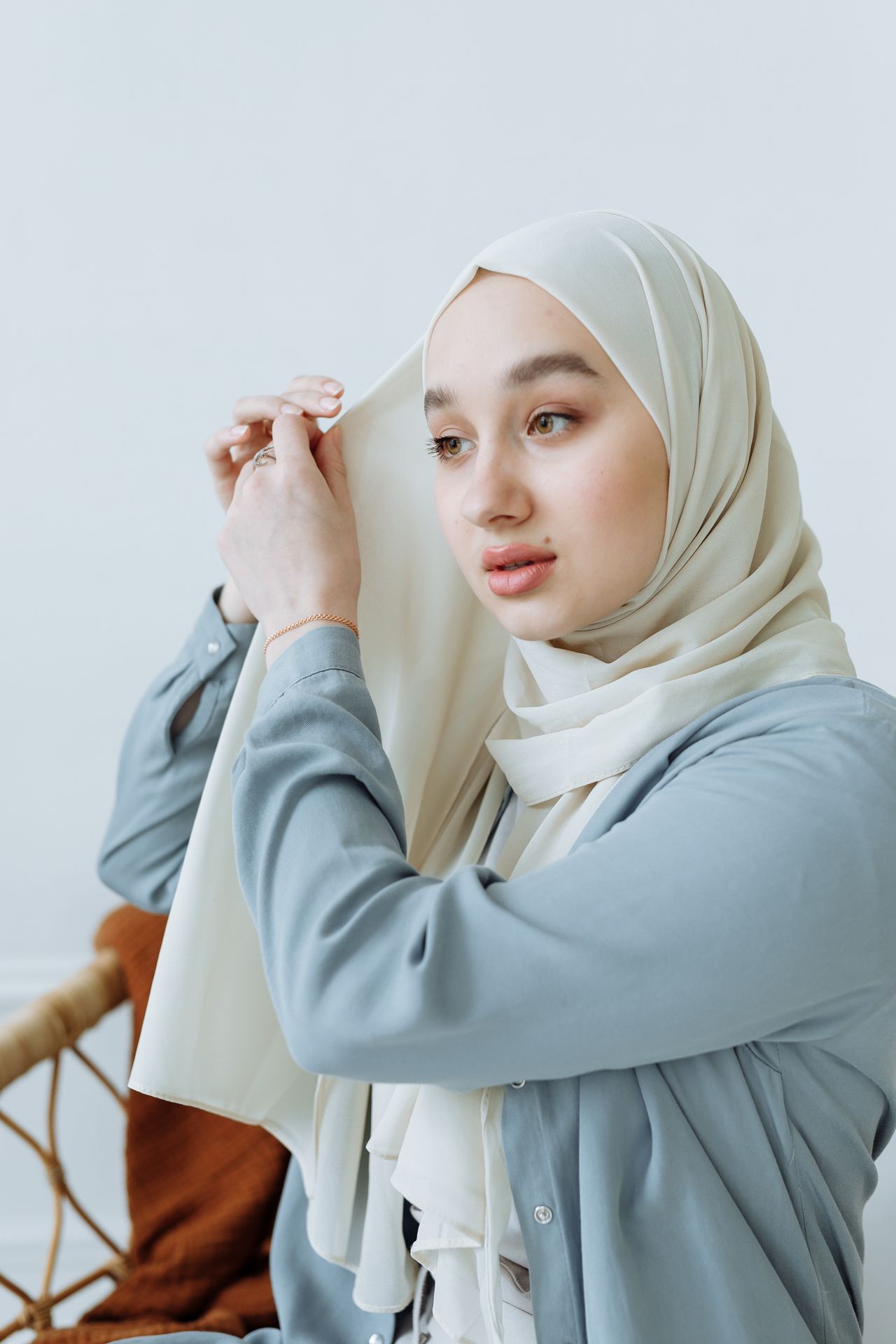 Woman in a modest light-blue blouse adjusting her hijab