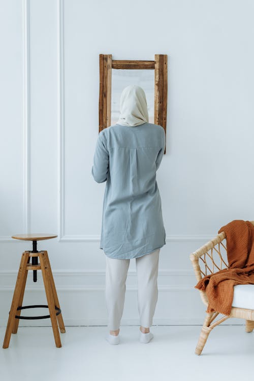 Free Back View of a Woman Wearing a Hijab Facing a Mirror Stock Photo