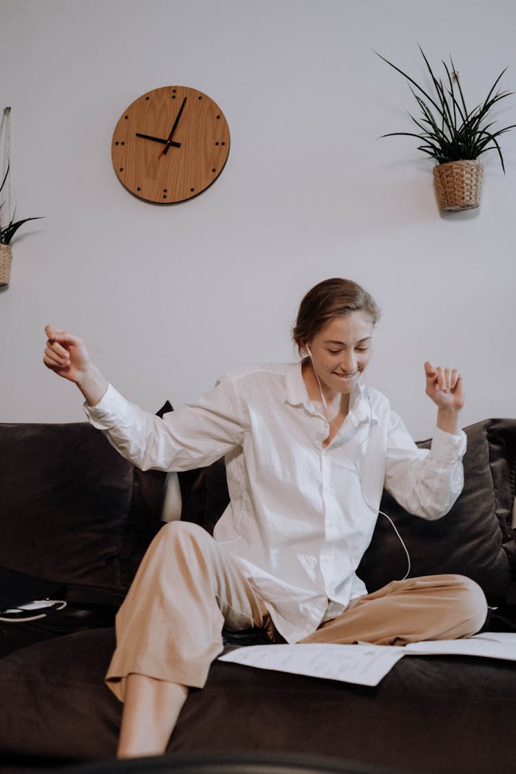 Woman In White Dress Shirt Sitting On Black Couch Listening To Music