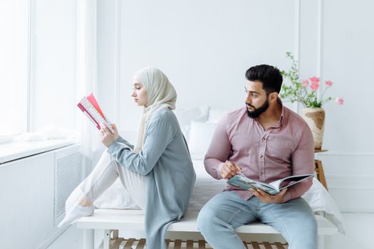 A Romantic Couple Sitting on the Bed while Reading a Book