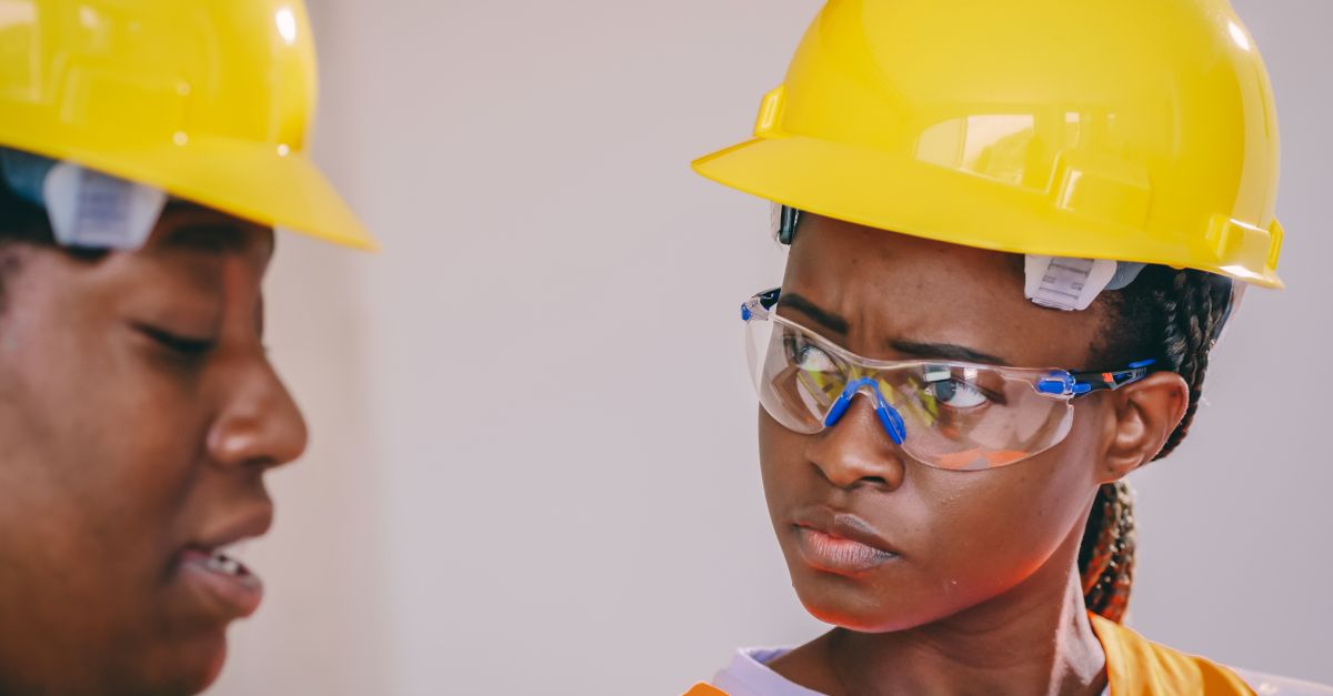 Nigerian oil rig workers in yellow hard hats inspecting equipment