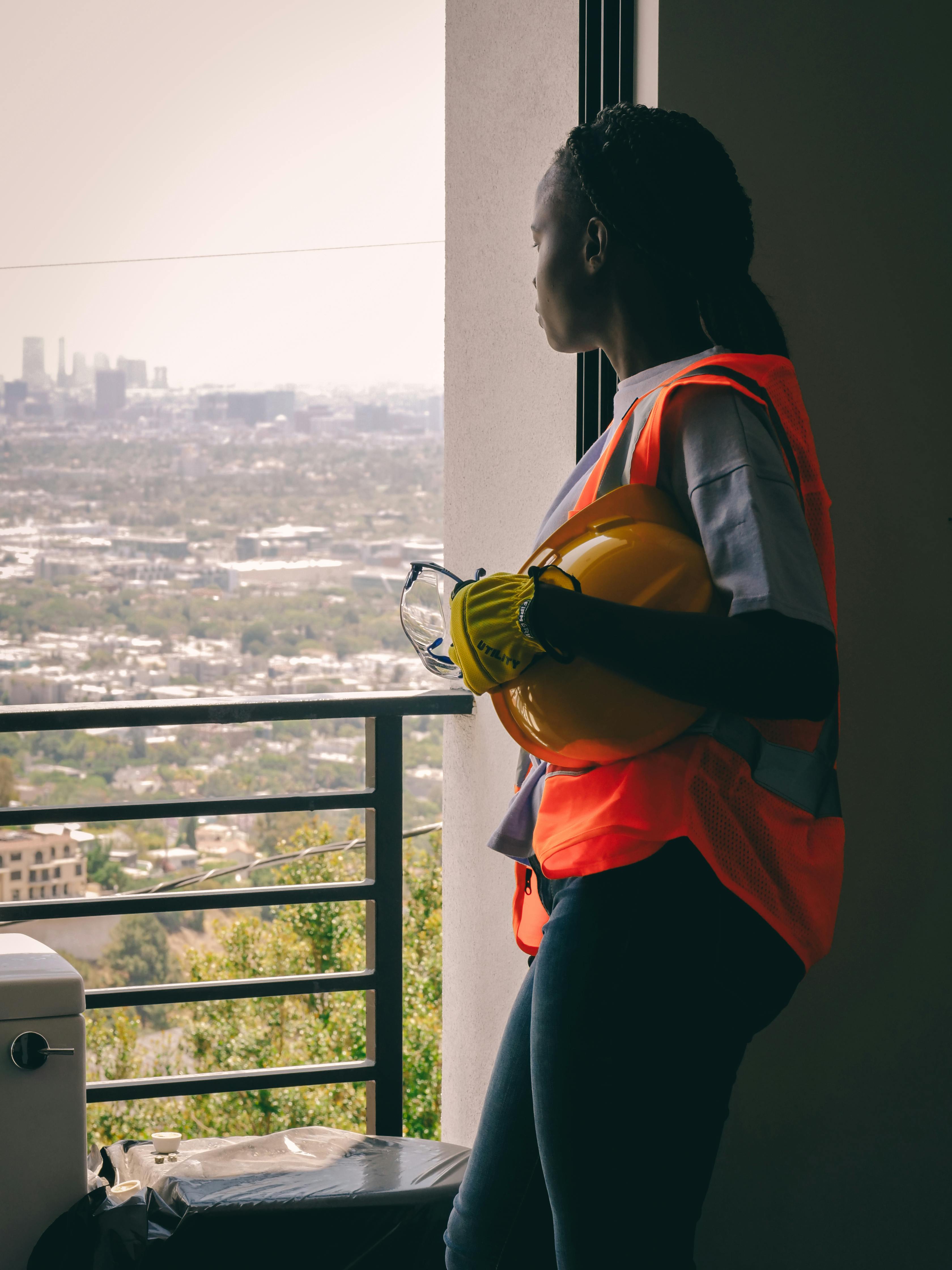Woman in Orange Shirt and Blue Pants Standing Beside Railings Looking