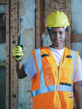 African American woman in construction attire, holding a tool, showcasing determination and safety.