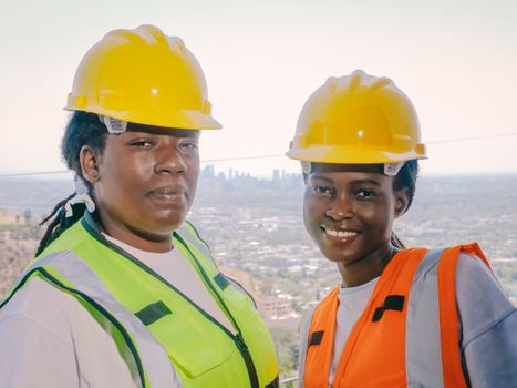 Two female construction workers wearing helmets and safety vests at a job site.