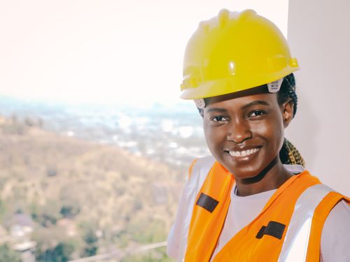 Free Black female engineer wearing safety gear and smiling, representing modern construction workforce. Stock Photo