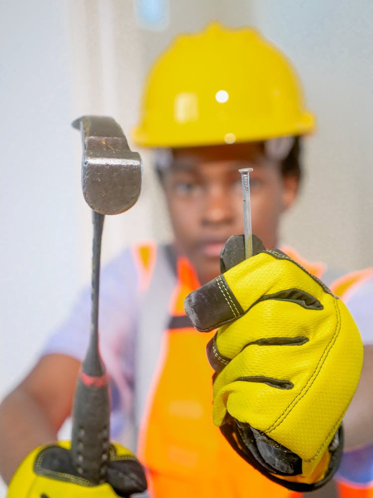 Person Holding Steel Nail And A Hammer