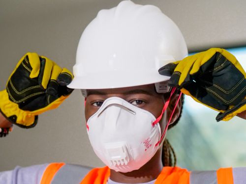 Free Construction worker wearing hardhat, N95 mask, and gloves for safety. Stock Photo