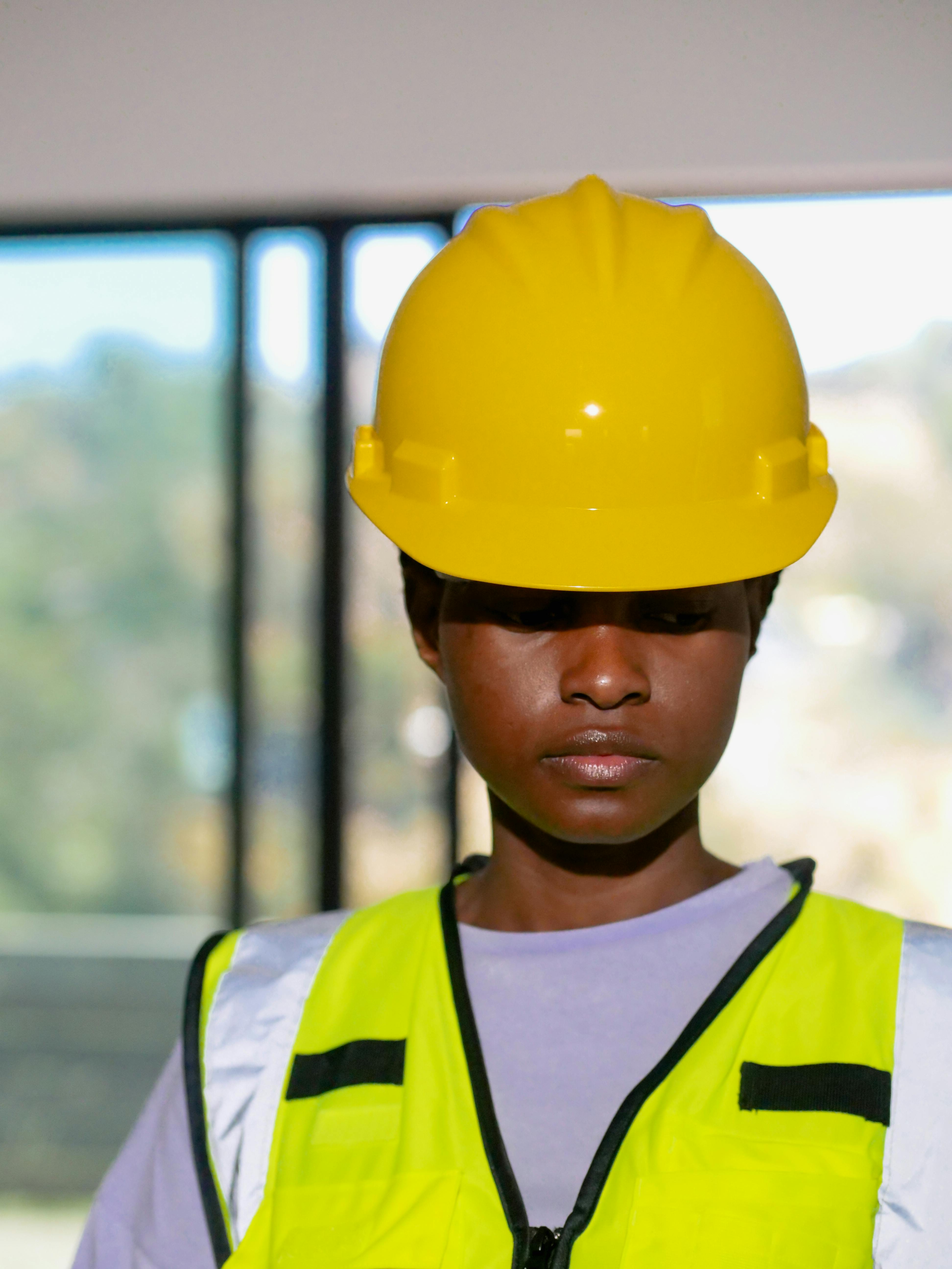 A worker wearing a yellow hard hat and safety glasses.