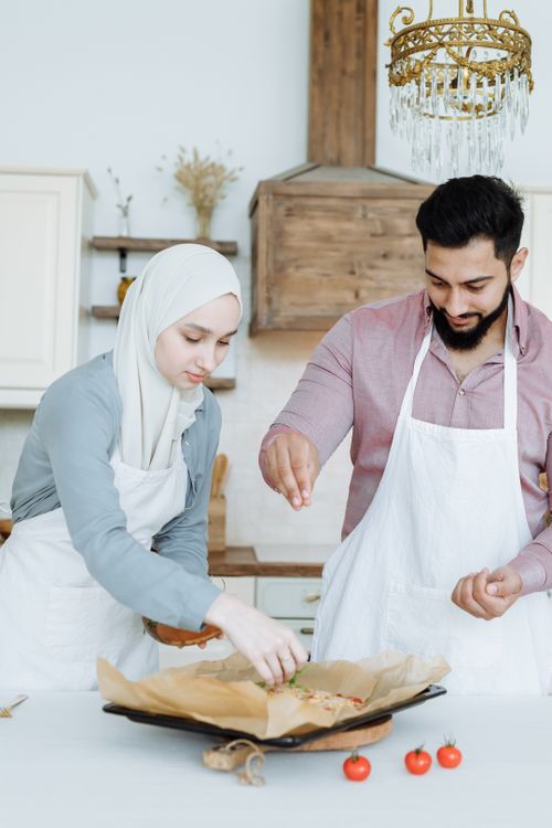 Free A Muslim couple preparing a meal in a modern kitchen with fresh ingredients and warm atmosphere. Stock Photo