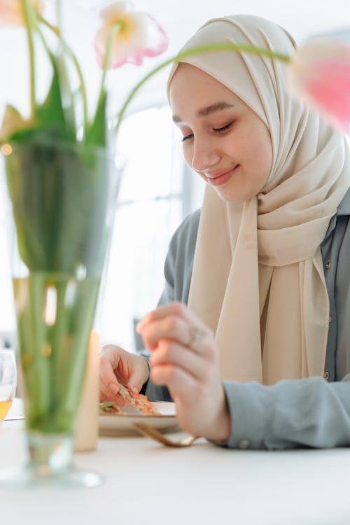 Smiling Woman in White Hijab Sitting by the Table