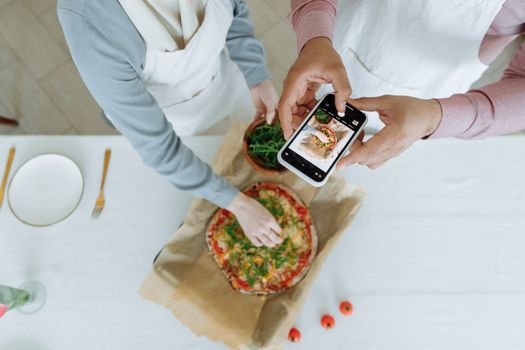 Capturing the moment of making a delicious homemade pizza with fresh ingredients from a high angle.