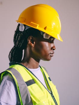 Side view of a female engineer wearing a hard hat and safety vest, showcasing workplace safety equipment.