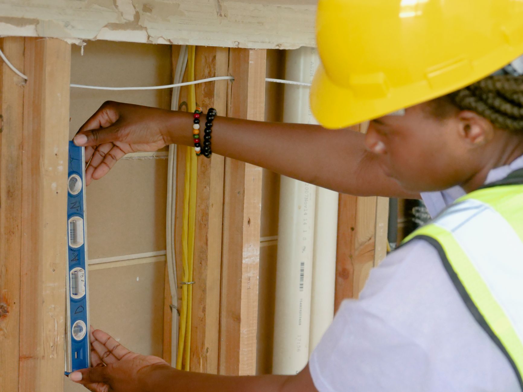 Construction worker in hardhat checking spirit level on wooden frame during a basement renovation in Woodstock. Construction worker in hardhat checking spirit level on wooden frame during a basement renovation in Woodstock.