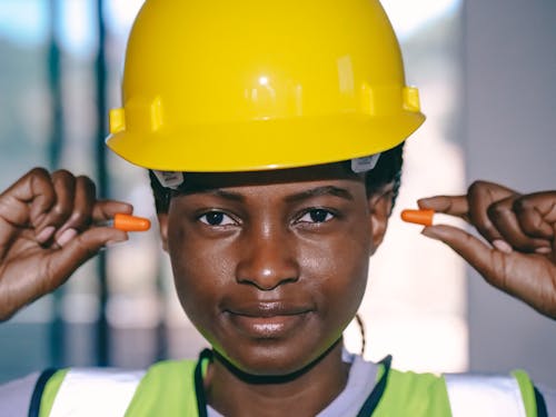 Free Construction Worker Putting Earplugs on her Ears Stock Photo