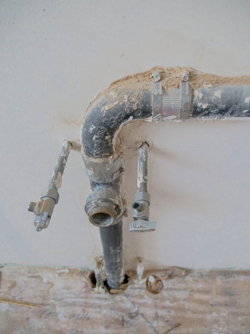Exposed plumbing pipes on a construction site wall — residential repair