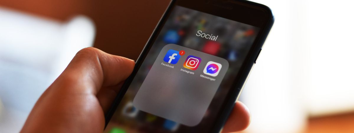 Mano con un móvil que muestra apps de redes sociales