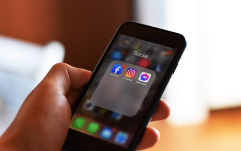 Mano con un móvil que muestra apps de redes sociales