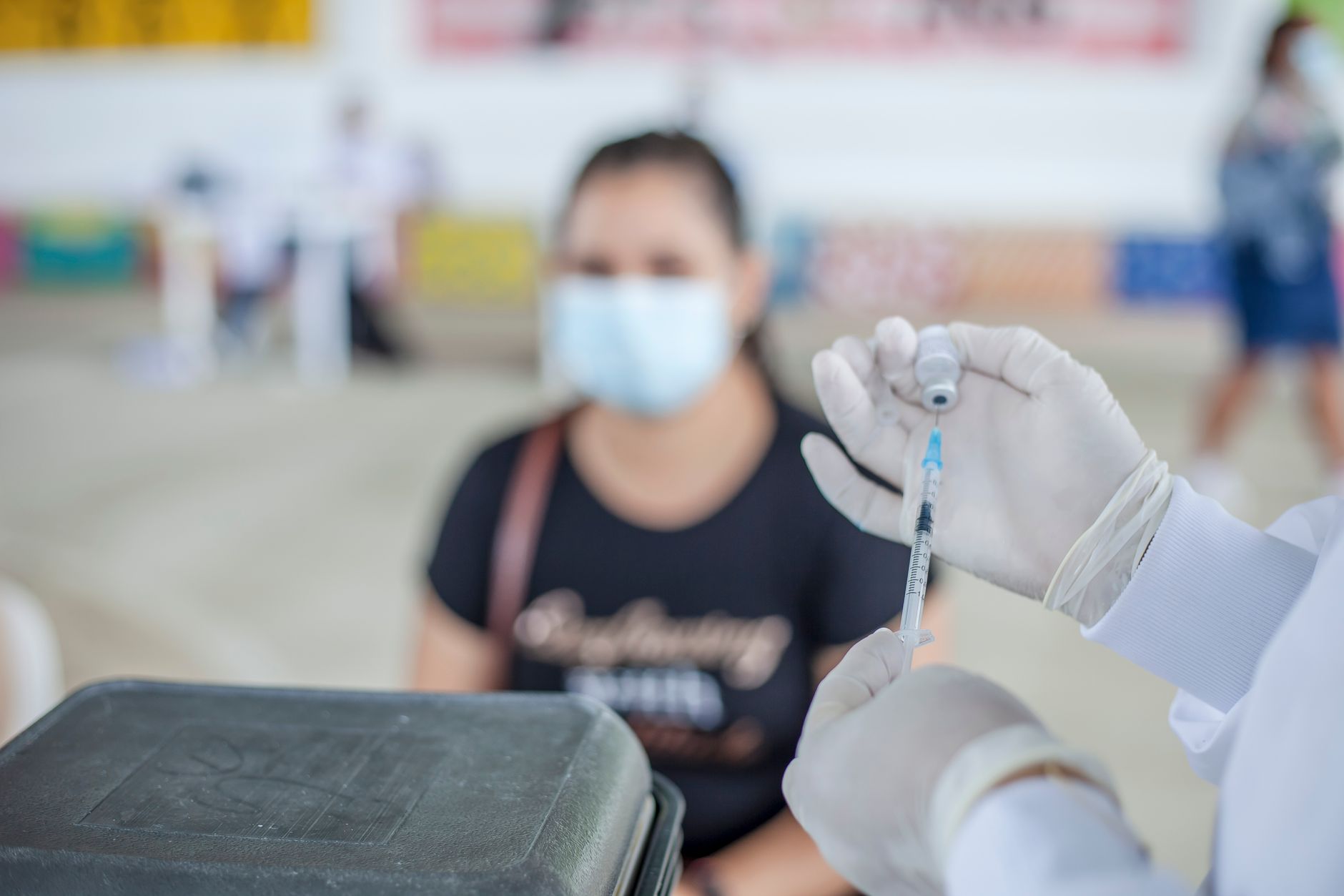 Healthcare worker prepares vaccine for patient in an indoor clinic setting.