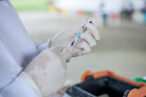 A Medical Practitioner Transferring Vaccine to the Syringe