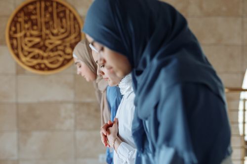 Free Three women wearing hijabs praying together indoors, focused and peaceful. Stock Photo