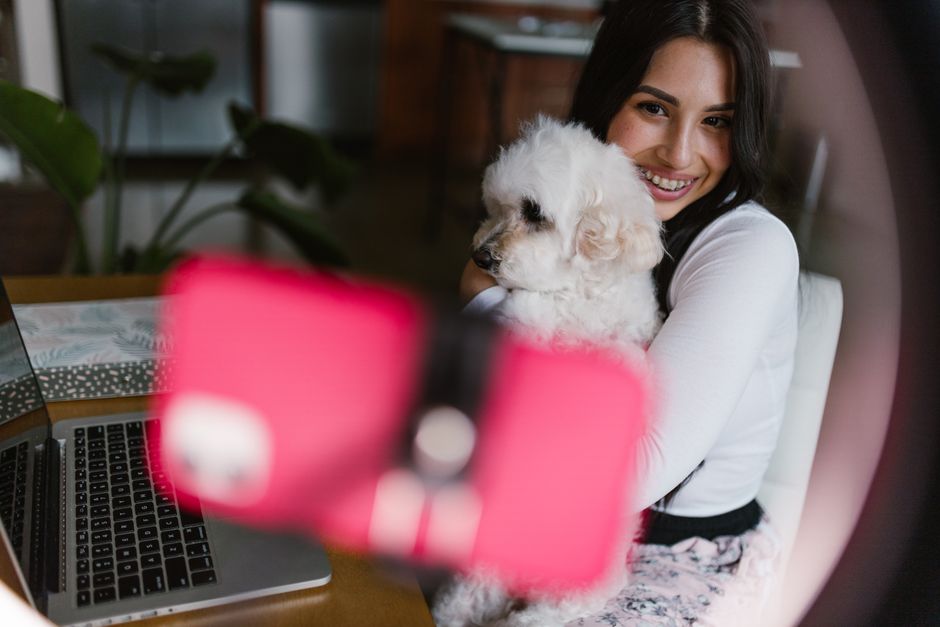 Woman smiling while working from home office with her fluffy pet dog. Cozy and productive home work setting.