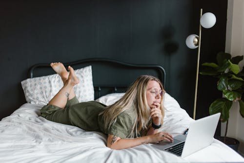 Woman Lying on Bed while Using Laptop