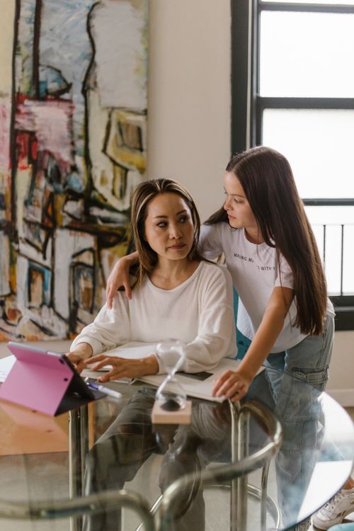 Free Mother and daughter share a moment in a bright home office, embracing creativity and connection. Stock Photo