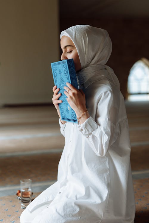 Free Person in White Long Sleeve Shirt Holding Blue Book Stock Photo