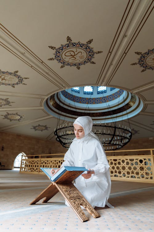 A Woman in White Hijab Reading a Book
