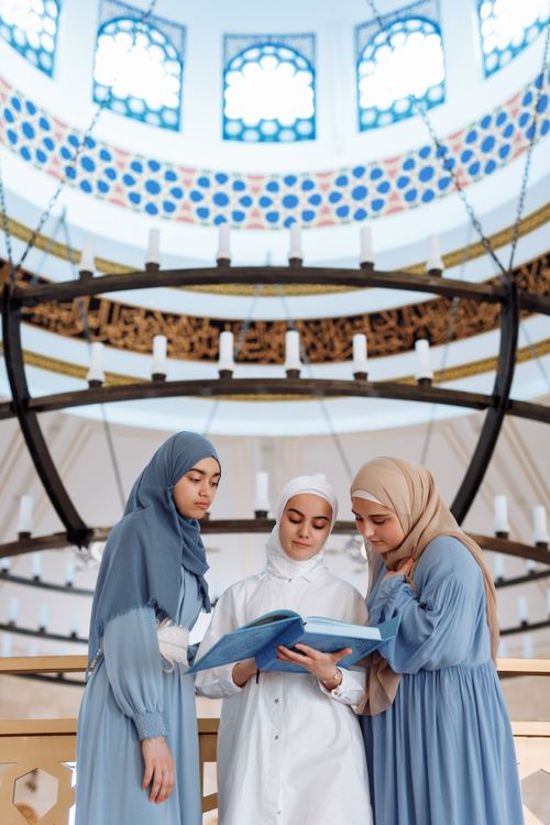 Free Three women in a mosque read a holy book during Ramadan. Peaceful and spiritual scene. Stock Photo