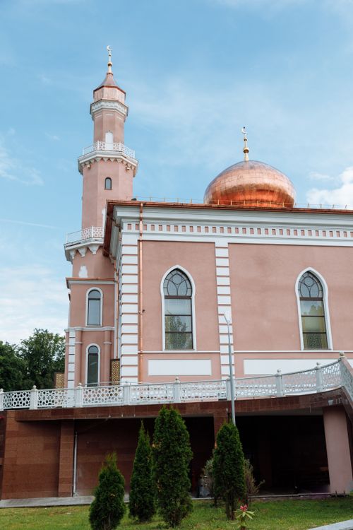 Free A beautiful pink mosque with a copper dome and tall minaret under a bright blue sky. Stock Photo