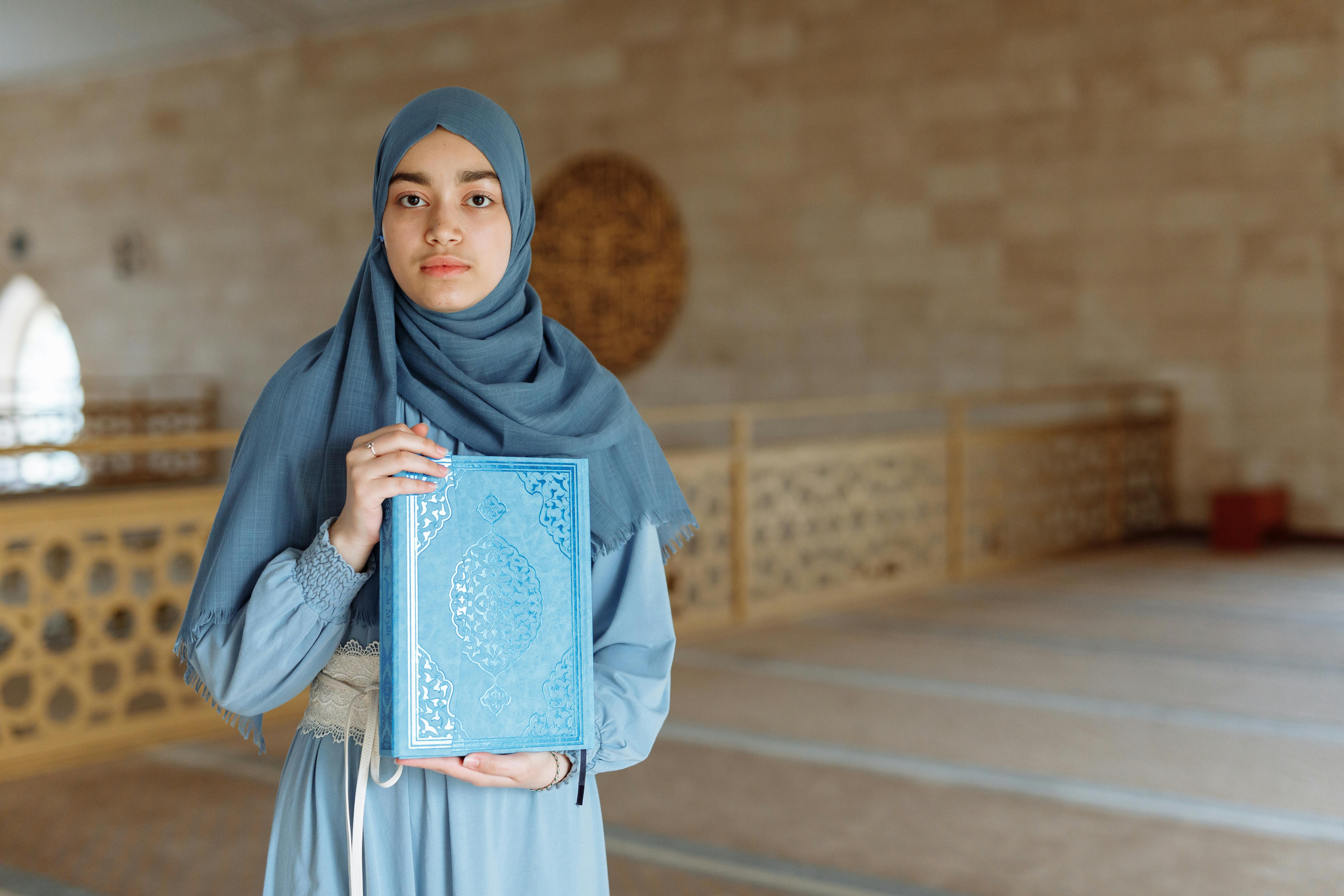 woman in blue hijab holding blue book