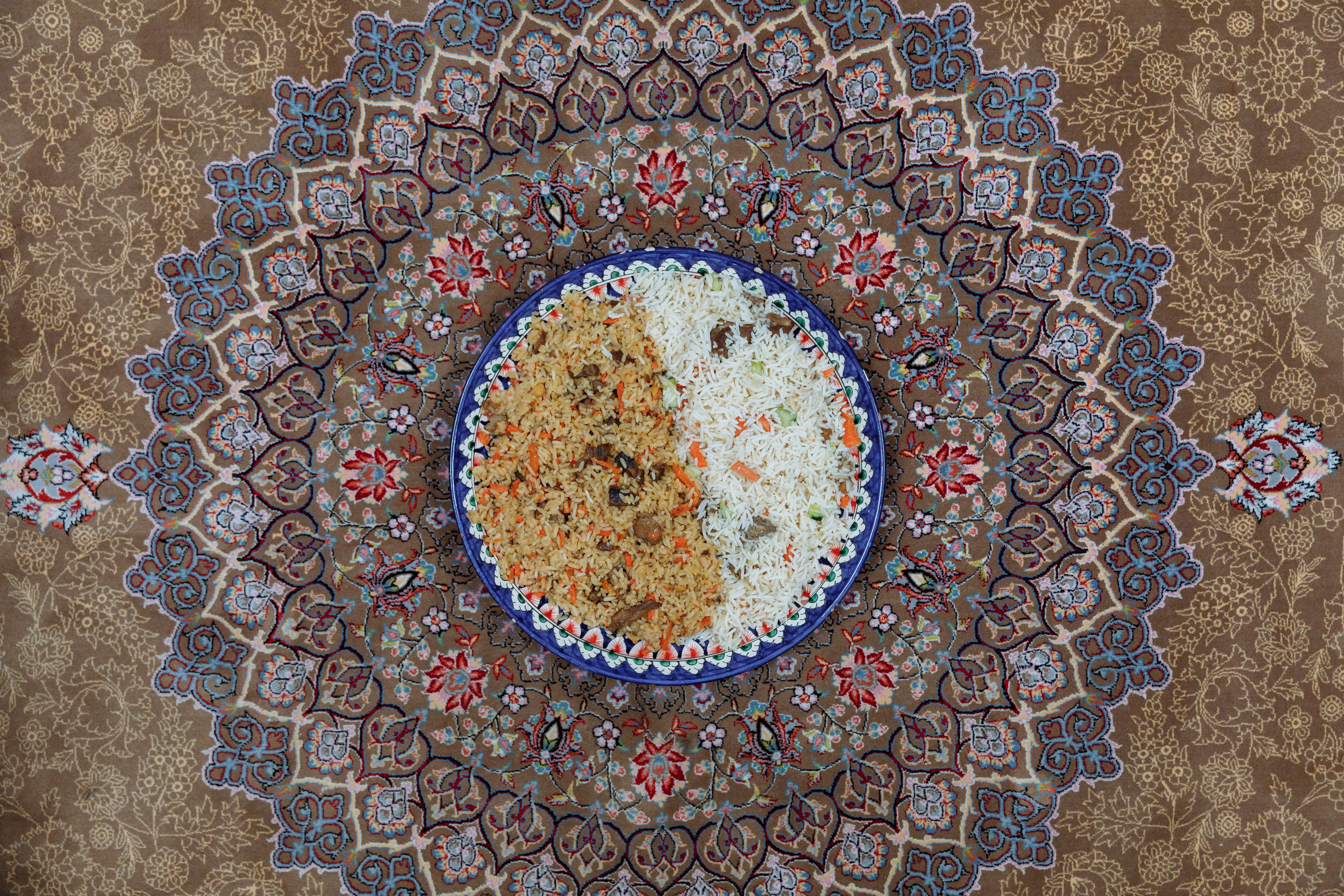 Top view of a delicious traditional rice dish served on an intricately designed Persian carpet.