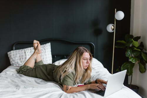 Free Woman Lying on Bed Typing on a Laptop  Stock Photo
