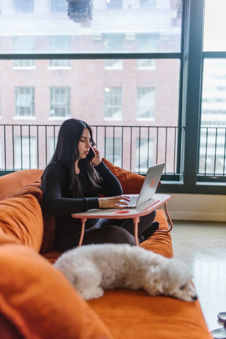 A Woman Having A Phone Call And Using A Laptop