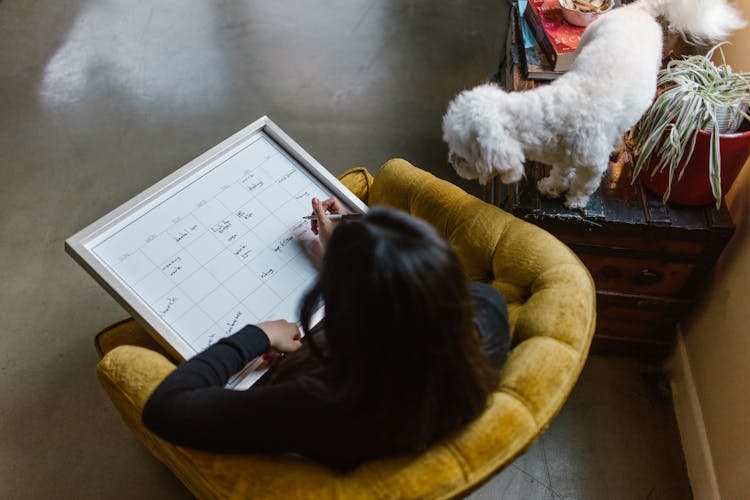 A Woman Writing On A Calendar