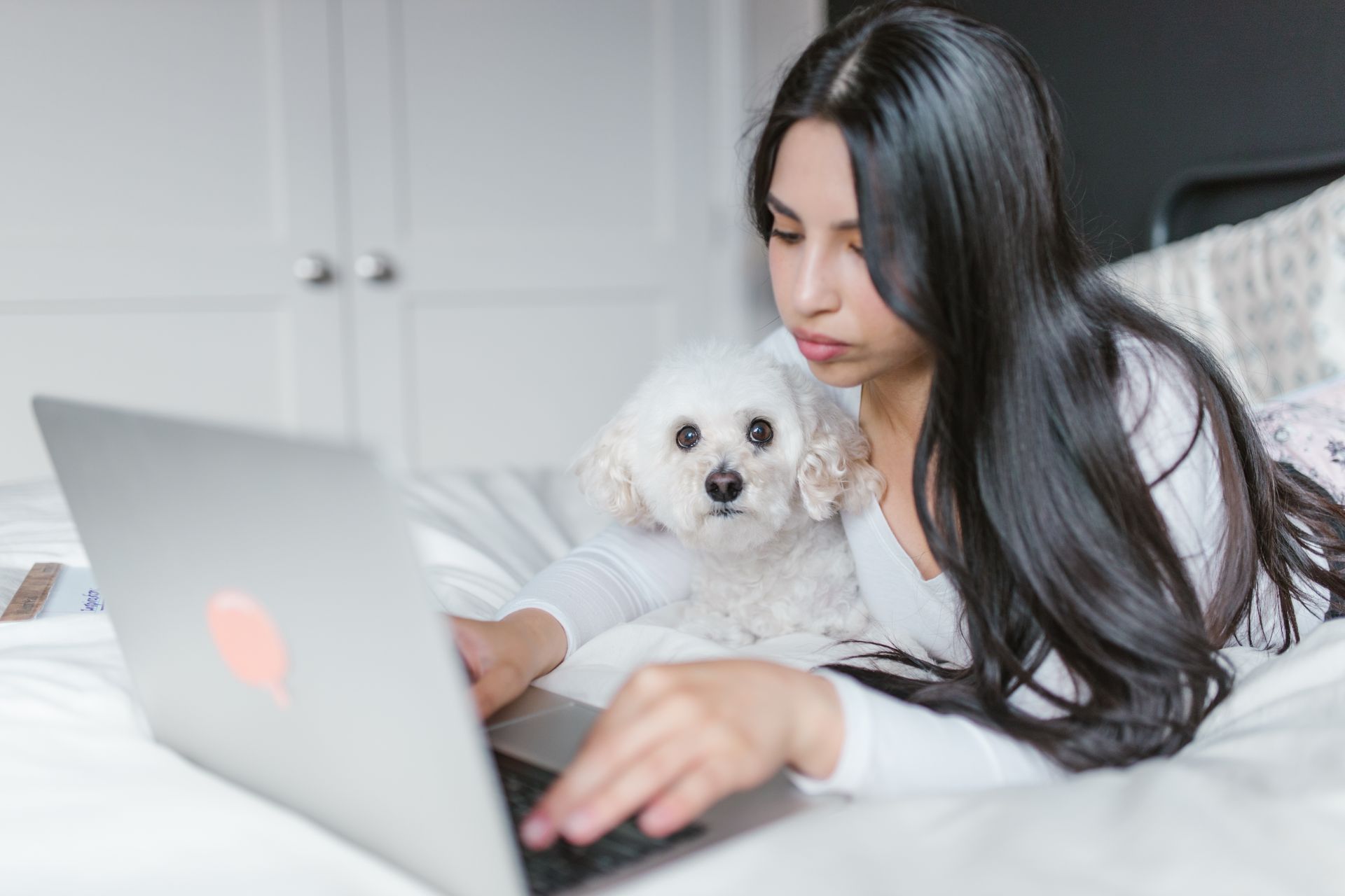 Woman Lying on a Bed While Using a Laptop