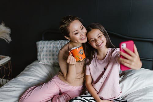 Free Woman and a Girl Taking a Photo on a Bed Stock Photo