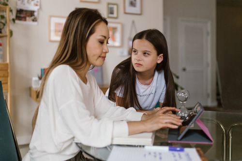 Free Mother and daughter engaged with a tablet at a home office setting. Stock Photo