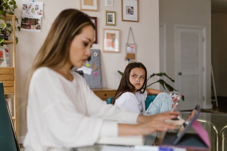 Angry Girl Looking At The Woman Using Table Computer 