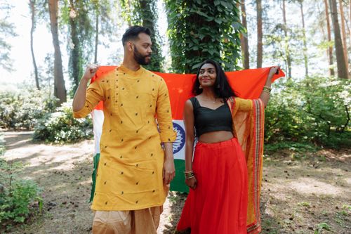 Free A couple in traditional Indian clothing holds the national flag outdoors, symbolizing cultural pride. Stock Photo