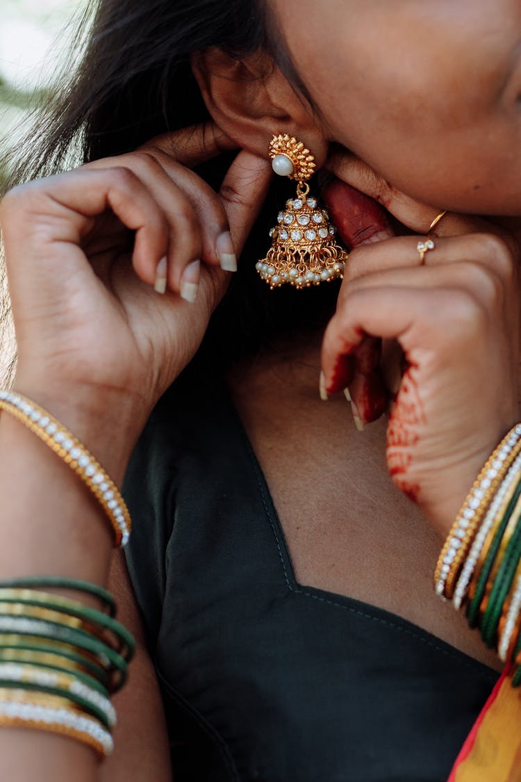 Woman Putting On A Gold Earring