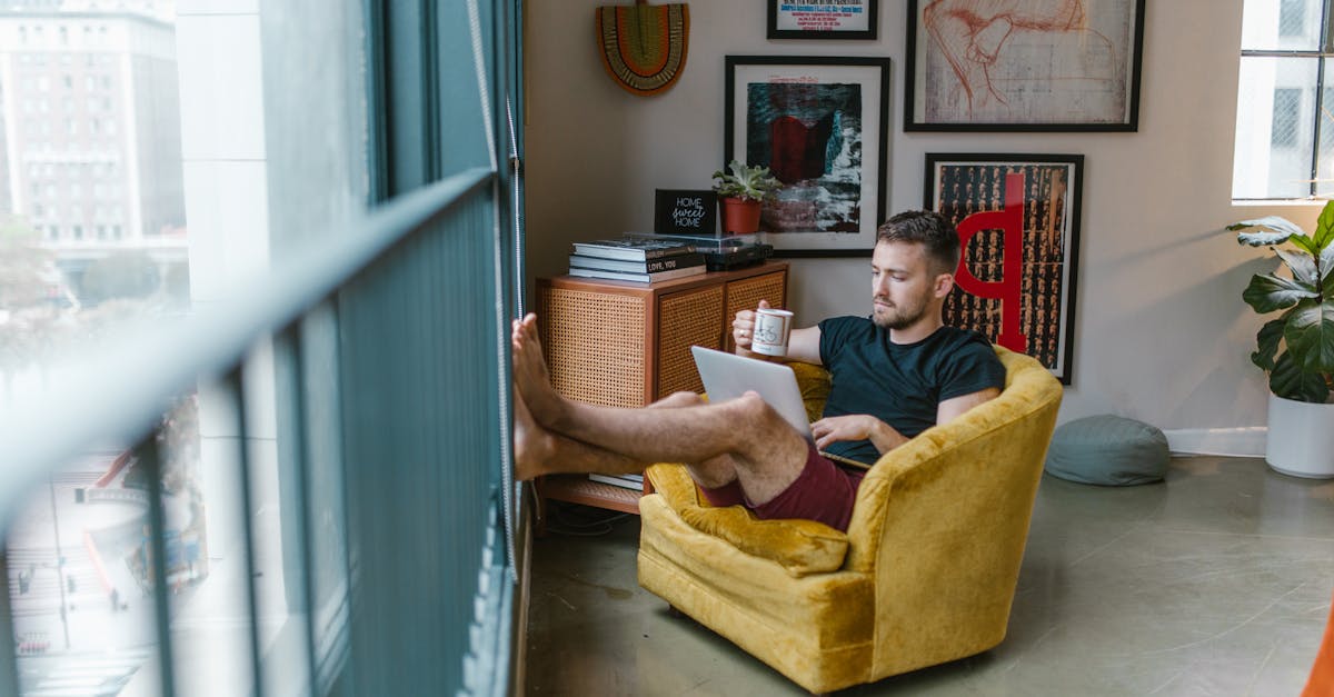 person looking at a sunrise from a window, laptop open, coffee in hand