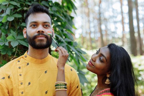Free A joyful couple engaging in face painting outdoors symbolizing Indian pride and culture. Stock Photo