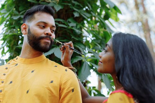 Free A couple engaging in a traditional face painting ritual outdoors, surrounded by greenery. Stock Photo
