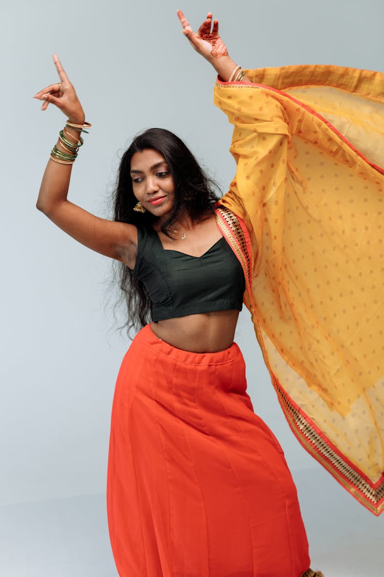 A Smiling Woman In Black Tank Top Wearing Bangles While Raising Her Hands